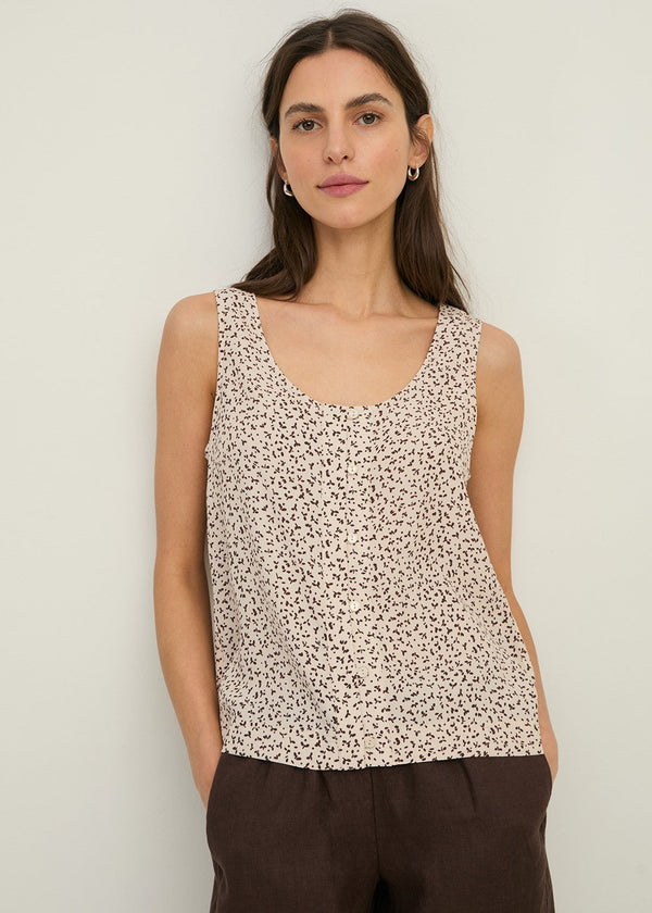 Woman wearing a patterned sleeveless top against a plain background