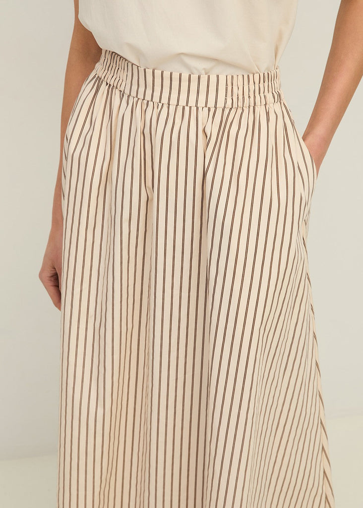 Beige and brown striped pants worn by a person on a plain background