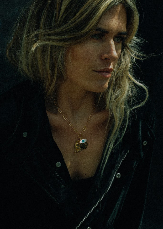 Woman wearing a necklace with a pendant against a dark background
