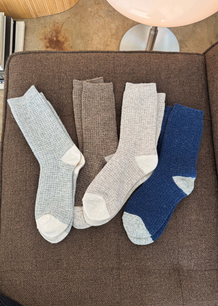 Four pairs of socks in gray and blue on a brown surface