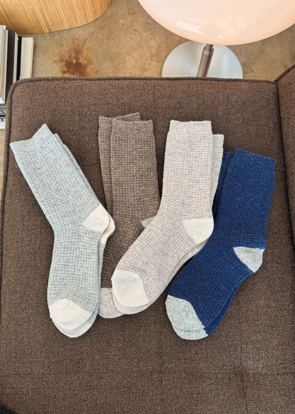 Four pairs of socks in gray and blue on a brown surface