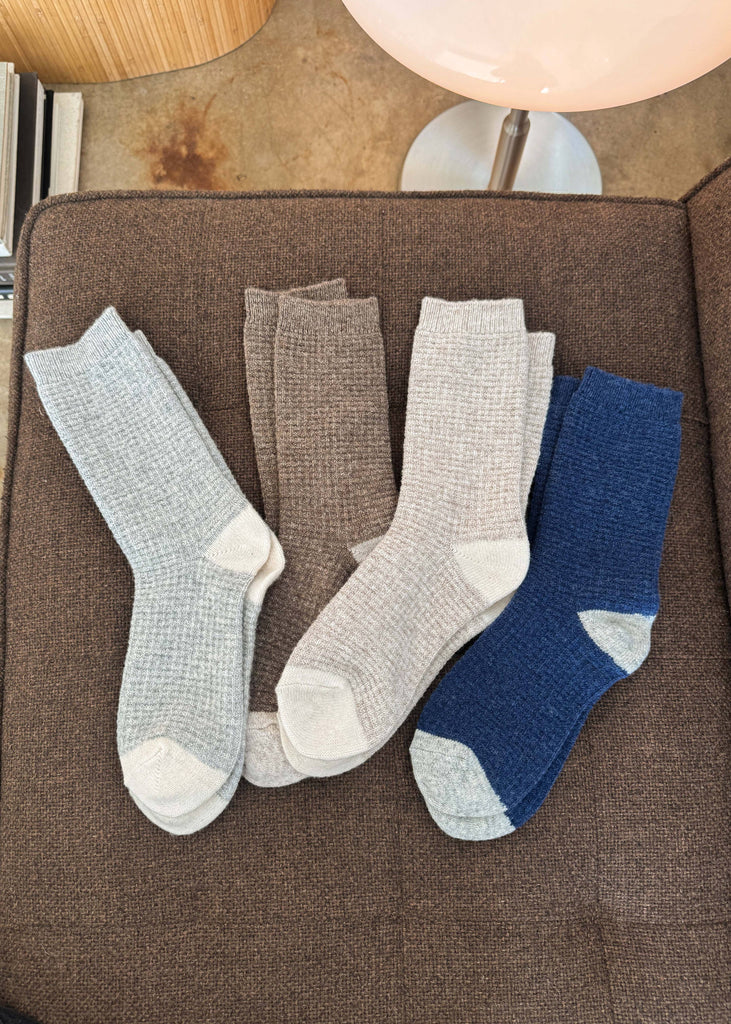 Four pairs of socks in gray and blue on a brown surface