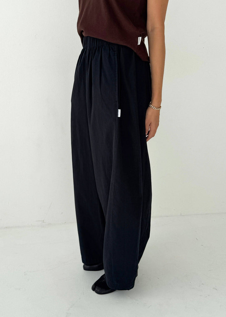 Person wearing black wide-leg pants and a brown top on a white background