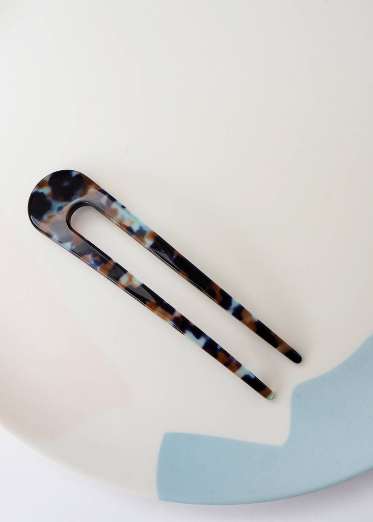 Tortoiseshell patterned hair clip on a white plate with a light blue edge.