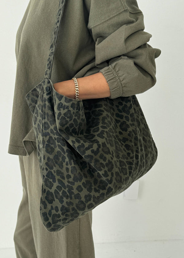 Person holding a leopard print bag against a white background