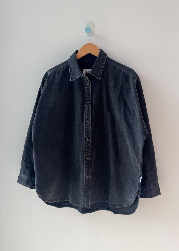 Dark denim shirt on a hanger against a white background