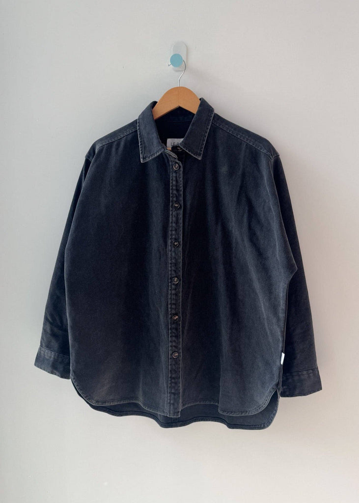 Dark denim shirt on a hanger against a white background