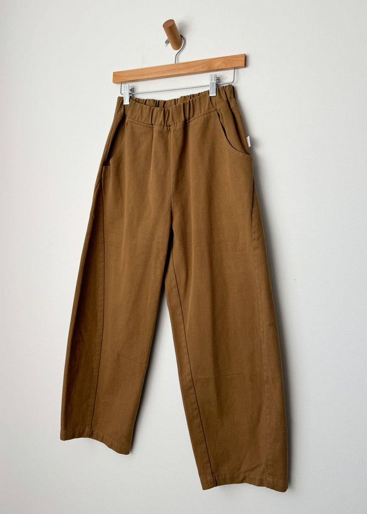 Brown pants hanging on a wooden hanger against a white background