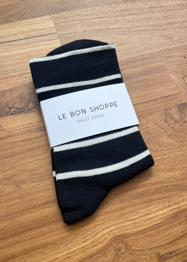 Black and white striped sock with 'Le Bon Shoppe' label on a wooden surface
