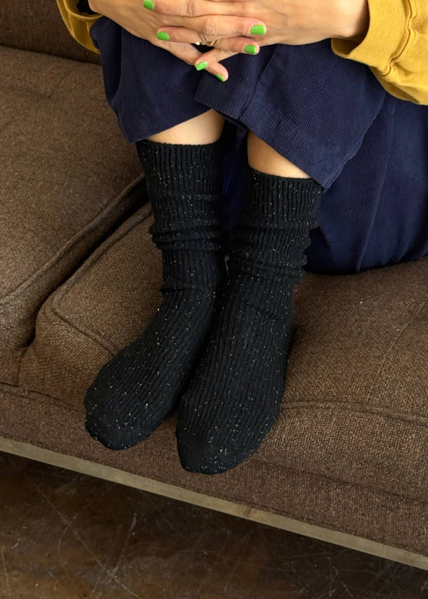 Person wearing black socks sitting on a brown couch