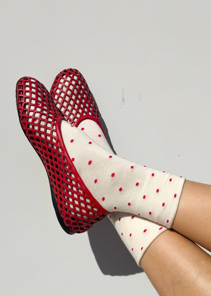 Red mesh shoes and white socks with red polka dots on a gray background