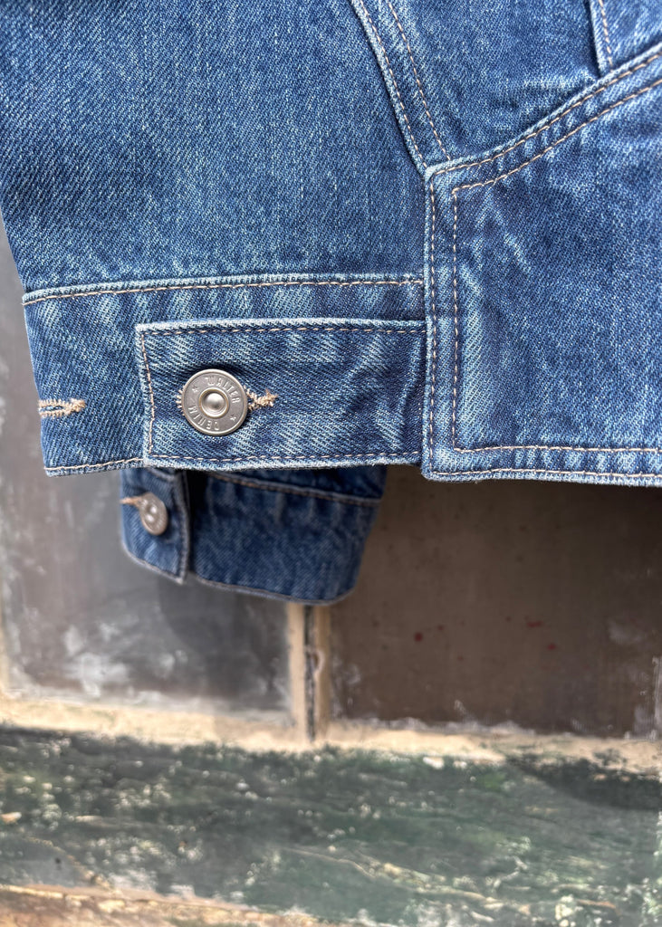 Close-up of a blue denim jacket with buttons on a textured surface