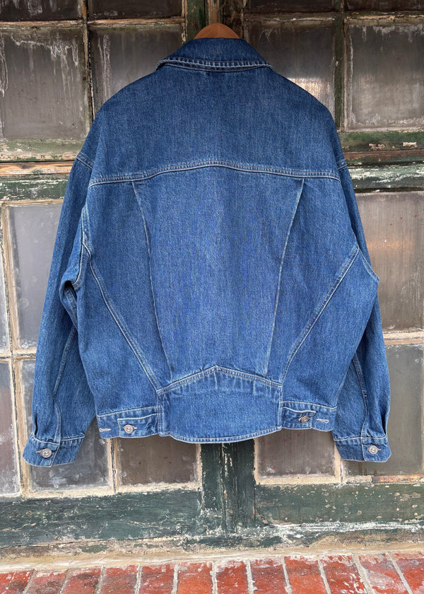 Blue denim jacket hanging against a textured wall.