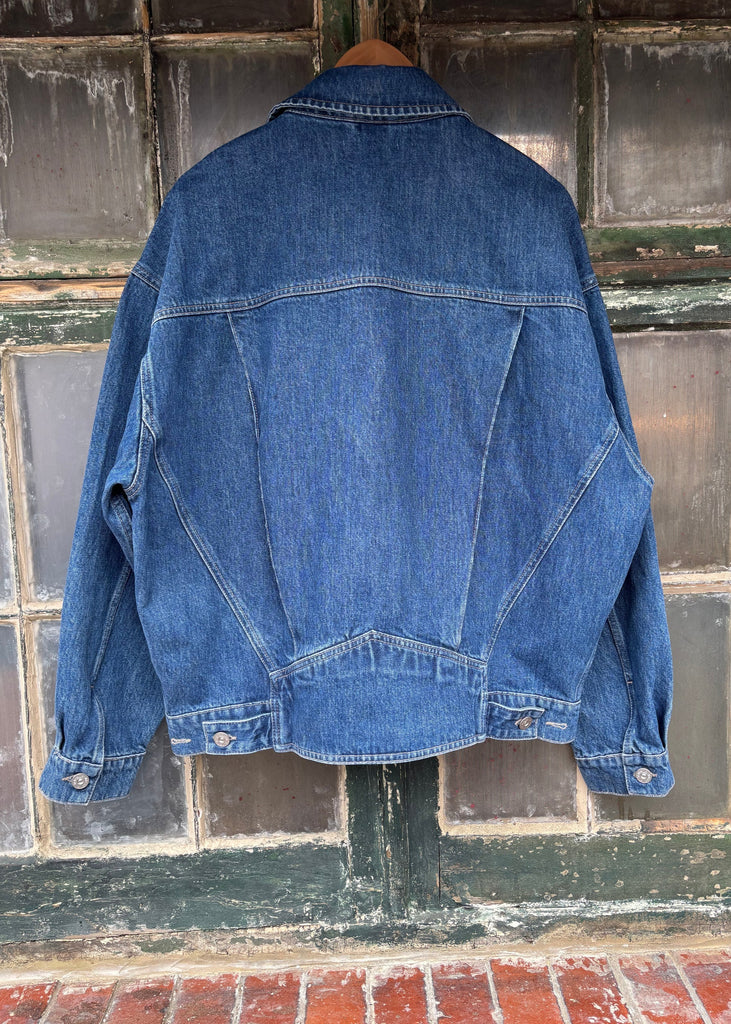 Blue denim jacket hanging against a textured wall.