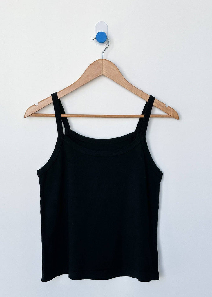 Black tank top on a wooden hanger against a white background