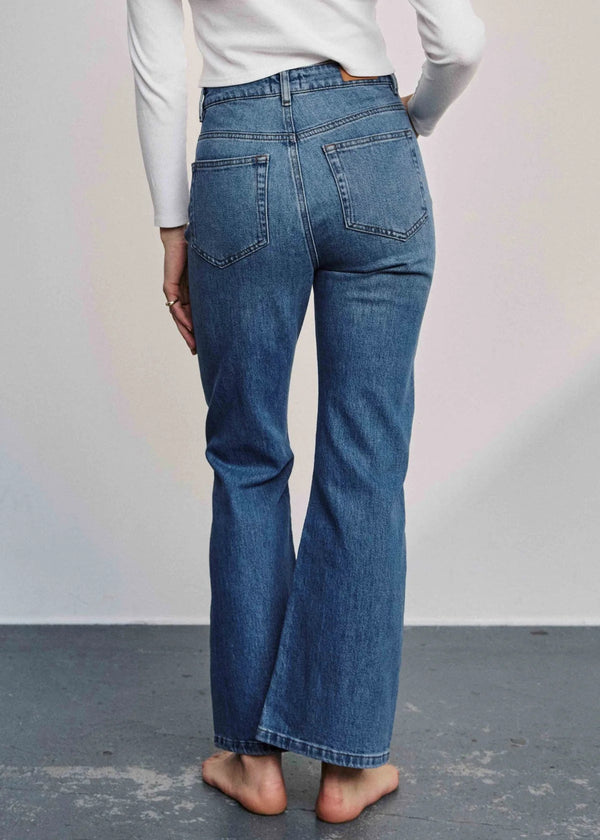 Person wearing blue jeans with a plain background
