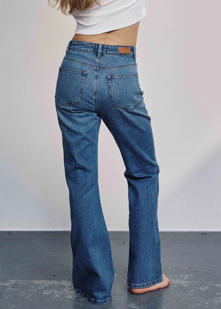 Person wearing blue jeans with a plain background