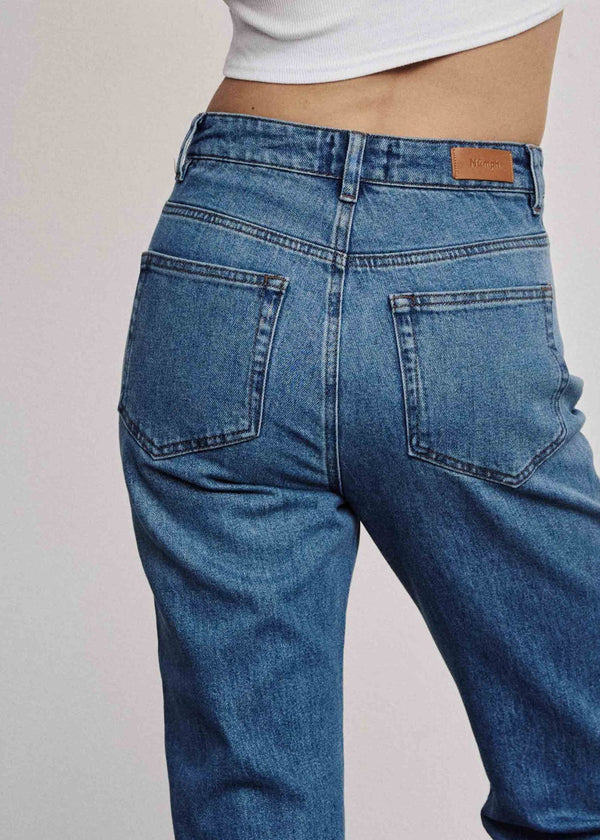 Blue jeans worn by a person on a plain background