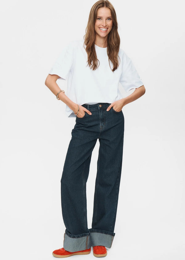 Woman wearing a white shirt and dark blue jeans on a white background