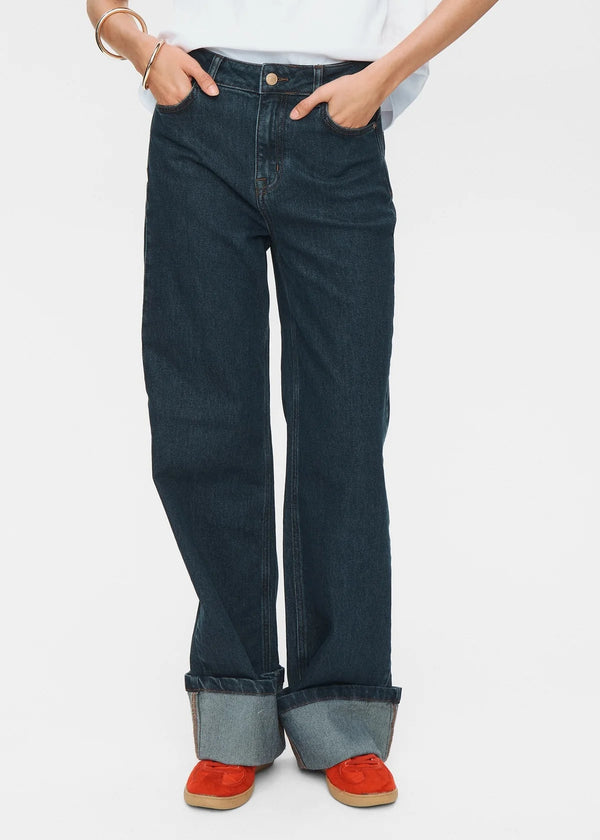 Person wearing dark blue jeans with red shoes on a white background