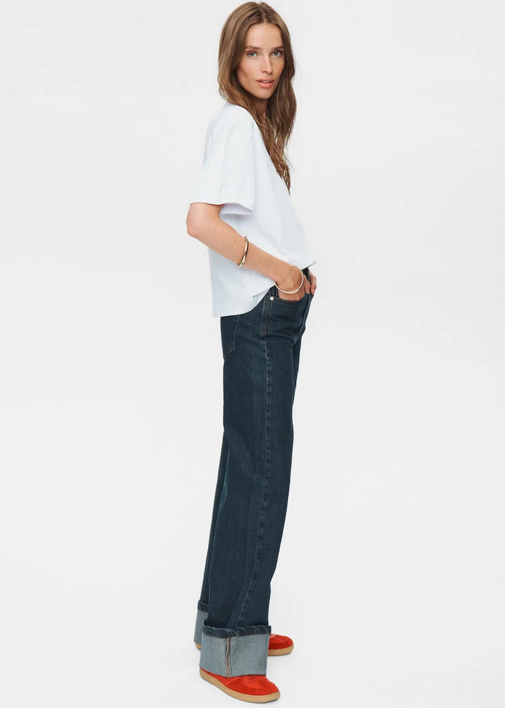 Woman wearing a white top and dark blue jeans on a white background