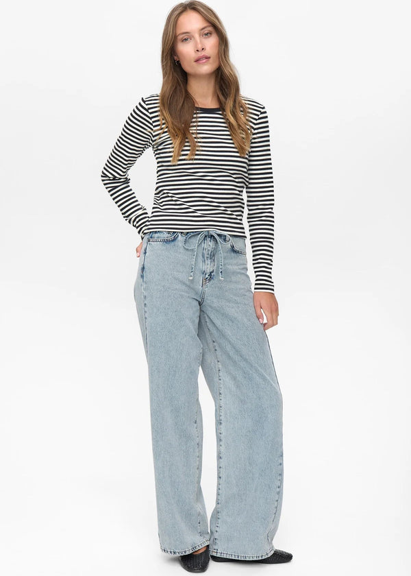 Woman wearing a striped shirt and light blue jeans on a white background