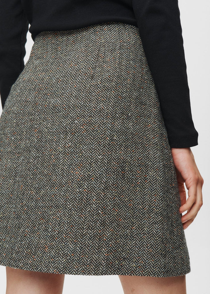 Gray herringbone patterned skirt worn by a person on a white background