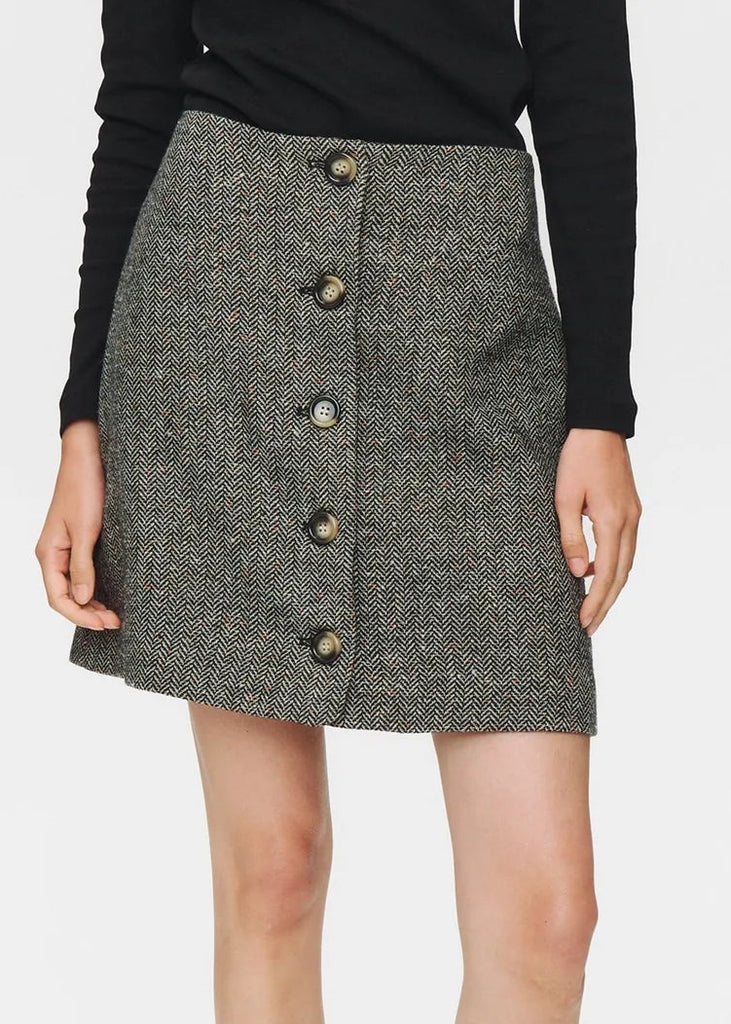 Person wearing a gray button-up skirt with a plain background