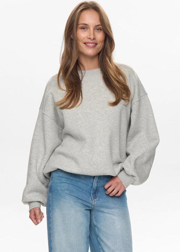 Woman wearing a gray sweater and blue jeans on a white background