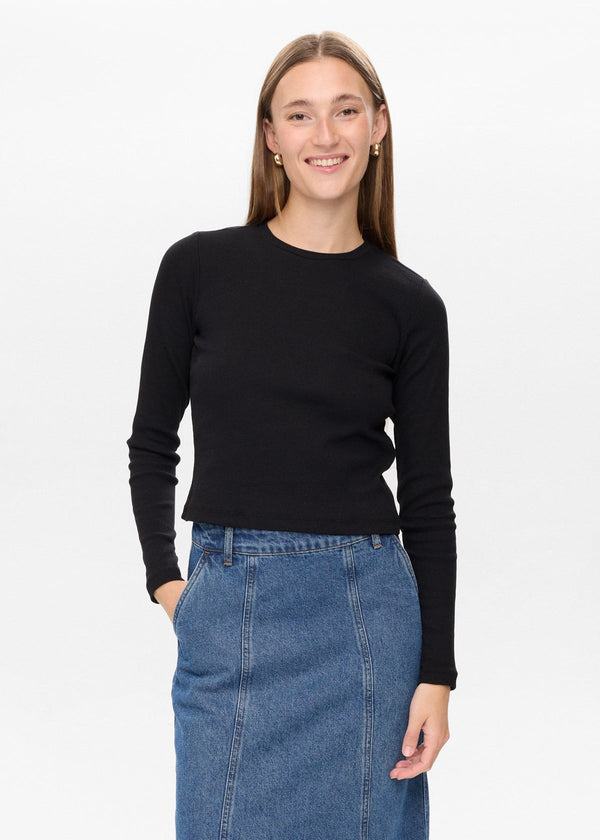 Woman wearing a black sweater and blue denim skirt on a white background