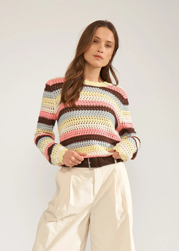 Woman wearing a colorful striped sweater against a plain background