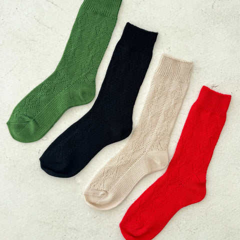 Four pairs of colorful socks (green, black, beige, red) on a light gray background.