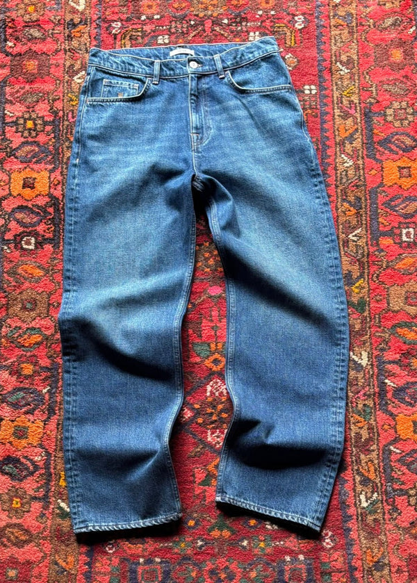 Blue jeans on a red patterned rug