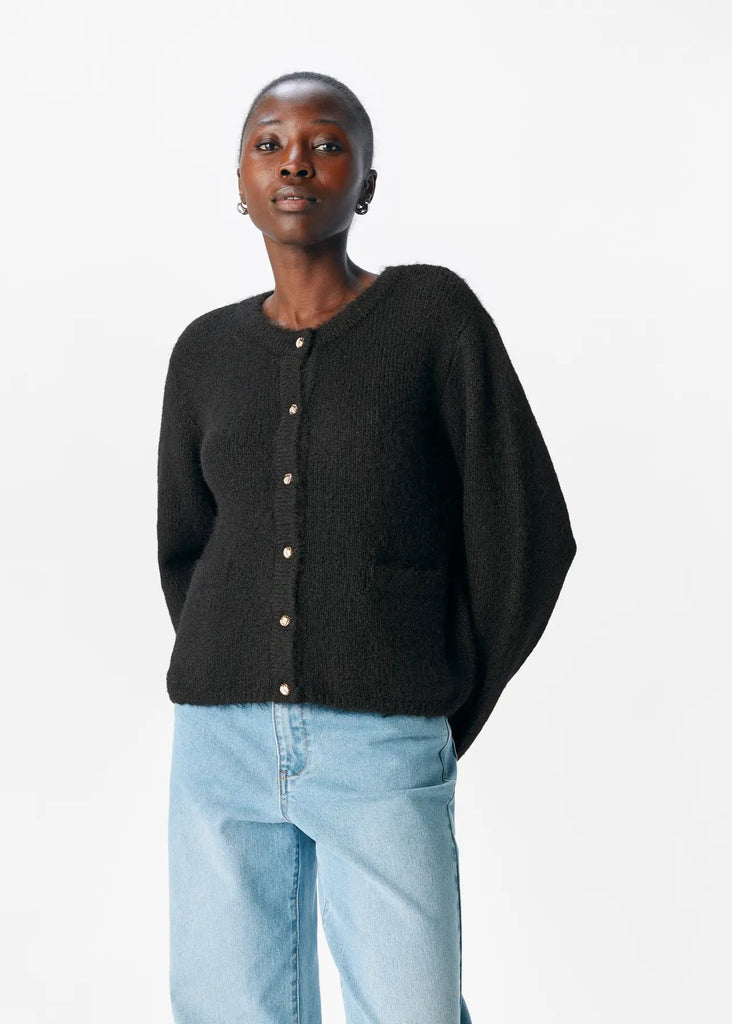 Person wearing a black cardigan and light blue jeans on a white background