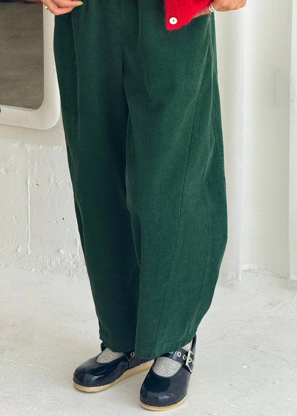 Person wearing green pants and red jacket on a white floor.