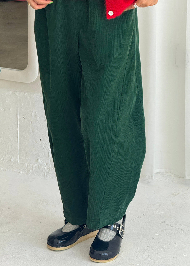 Person wearing green pants and red jacket on a white floor.