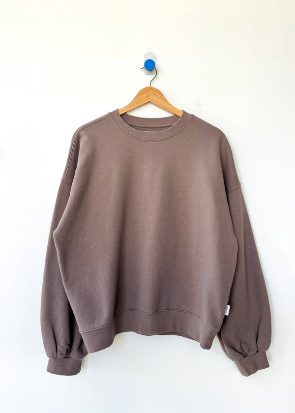Brown sweatshirt on a wooden hanger against a white background