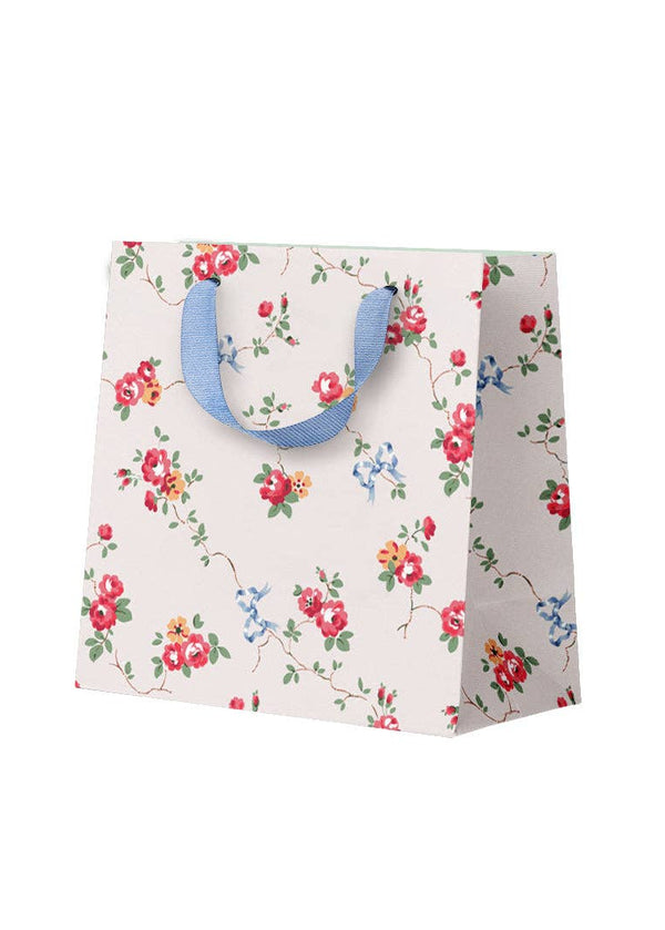 Floral-patterned paper bag with blue handles on a white background