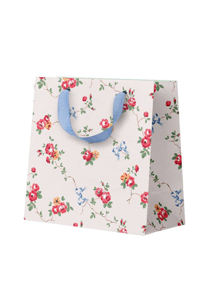 Floral-patterned paper bag with blue handles on a white background