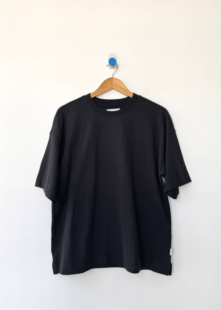Black t-shirt on a wooden hanger against a white background