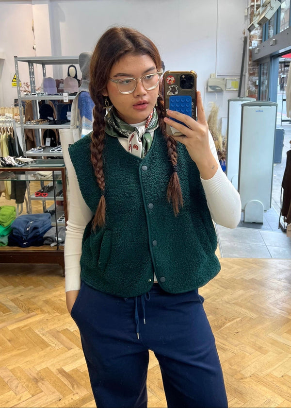 Person wearing a green vest and blue pants in a store setting