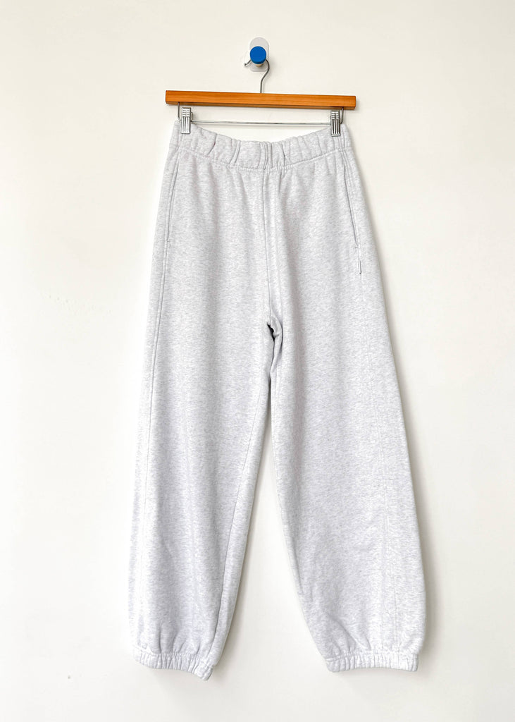 Gray sweatpants hanging on a wooden hanger against a white background