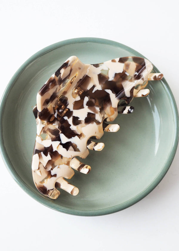 Decorative lizard-shaped object on a green plate with a white background
