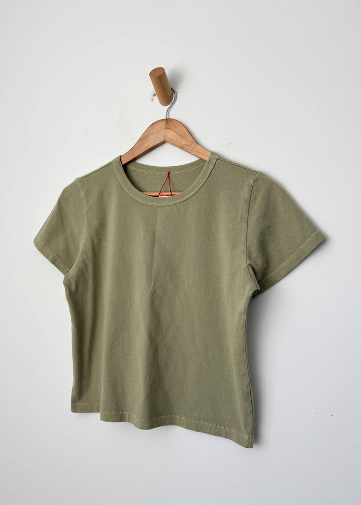 Green t-shirt on a wooden hanger against a white background
