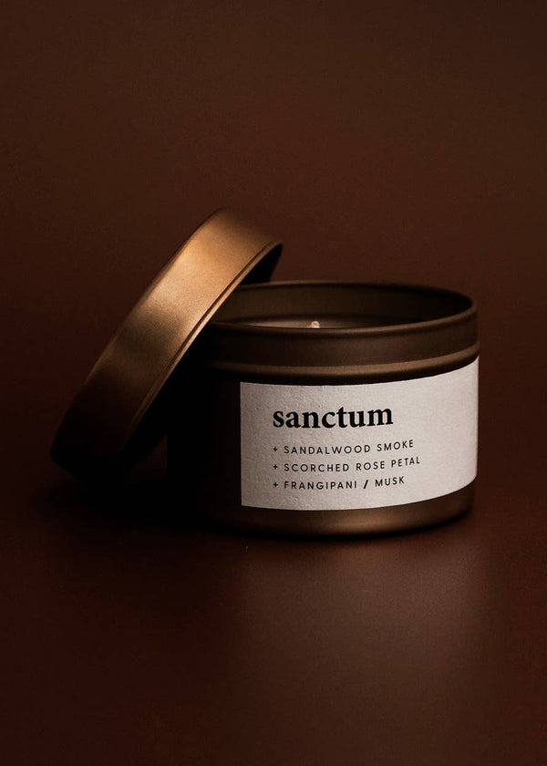 Candle jar labeled 'sanctum' on a dark brown background