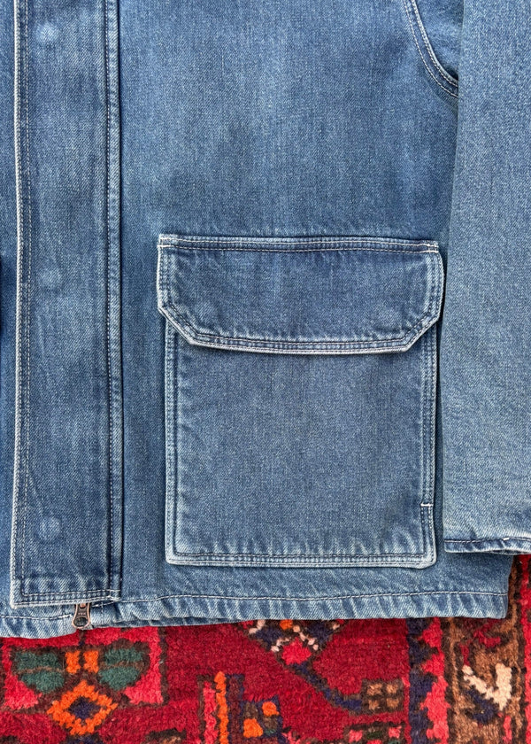 Close-up of a blue denim jacket with a pocket on a patterned rug