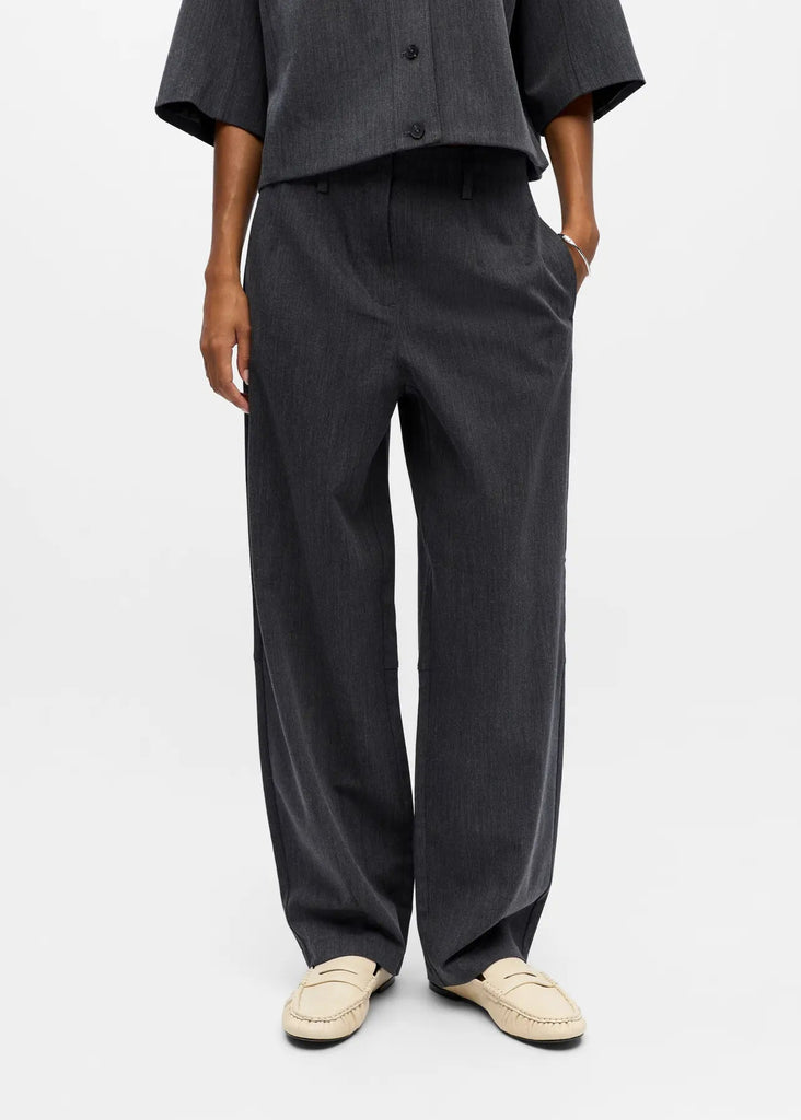 Person wearing a dark gray outfit with wide-leg pants on a white background