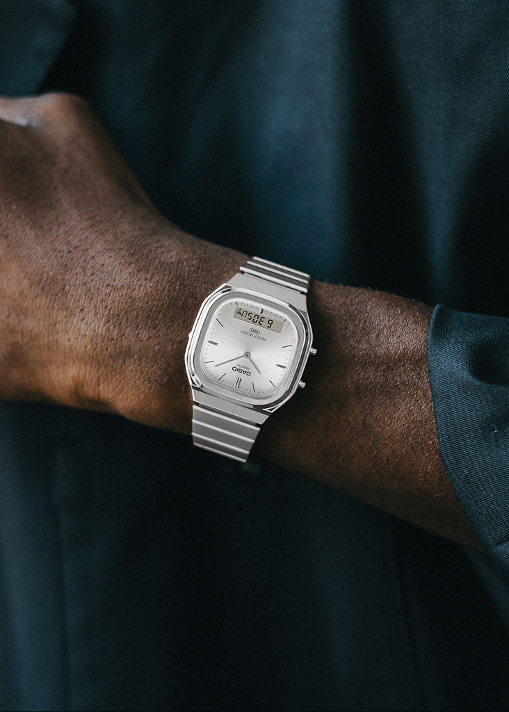 Person wearing a silver wristwatch with a dark shirt