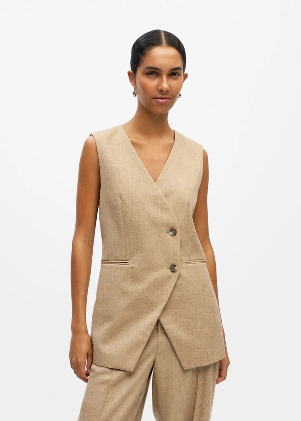 Woman wearing a beige vest and pants on a white background