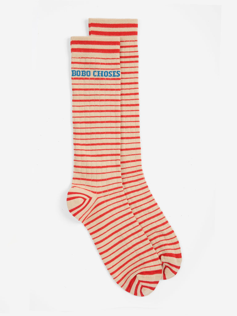 A pair of knee-high socks with horizontal red and cream stripes, featuring the text 'DOBO CHOSES' in blue on the upper cuff, displayed against a plain white background.